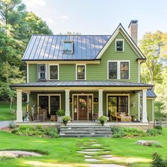 a green house with a metal roof and steps leading to the front door is shown