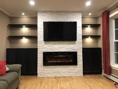 a living room with a couch, fireplace and television mounted on the wall above it