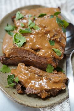 two pieces of steak covered in gravy on a plate