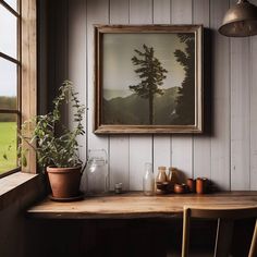 a painting hanging on the wall next to a table with two chairs and a potted plant