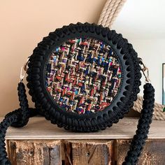 a round purse sitting on top of a wooden table next to a roped wall