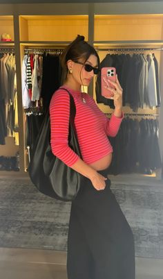 a woman taking a selfie with her cell phone in front of a clothing rack