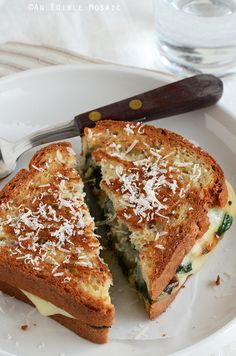 a white plate topped with a cut in half sandwich next to a knife and fork