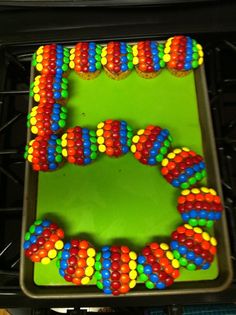 a cake decorated with multicolored beads on top of a green tray in front of a stove