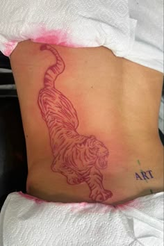 a tiger tattoo on the side of a woman's lower back, which is covered in pink ink