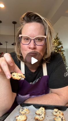 a woman in an apron is eating cookies