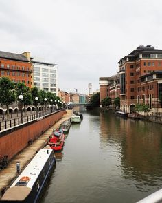 there are many boats that are docked in the water near some buildings on the other side of the river