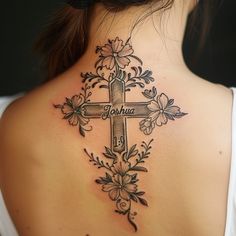 the back of a woman's neck with a cross and flowers tattoo on it