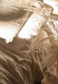 a bed with white sheets and pillows on top of it next to a night stand