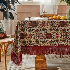 a table covered with a red, green and yellow floral design next to a potted plant