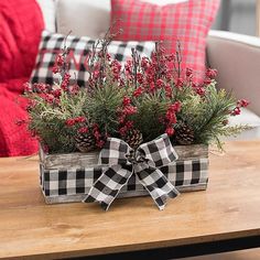 a wooden box filled with red berries and pine cones sitting on top of a table