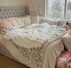 a bed that is made up with blankets on it and pillows in front of the headboard