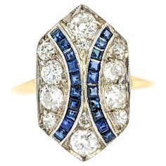 Old Mine Cut Diamond & Sapphire Shield Ring in Yellow Gold Introducing this beautiful Antique Ring, crafted in 18kt two-tone white and yellow gold. The ring features a .85ctw Old Mine Cut diamond centerpiece, accented by .20ctw sapphires in a shield ring design. The sparkling diamonds are VS-SI clarity and near colorless, enhancing the overall brilliance of the piece. Old Mine Cut diamonds, popular in the 1910s, are known for their unique charm and historical significance. These diamonds symboli Yellow Gold Multi-stone Art Deco Jewelry, Art Deco Multi-stone Yellow Gold Jewelry, Art Deco Yellow Gold Multi-stone Jewelry, Art Deco Multi-stone Diamond Ring, Art Deco Ring In Diamond White With Jewels, Hallmarked Platinum Cluster Ring In Yellow Gold, Art Deco Yellow Gold Ring With Diamond Accents, Collectible Multi-stone Yellow Gold Diamond Ring, Platinum Sapphire Ring With Brilliant Cut In Yellow Gold