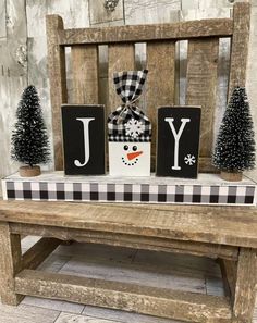 a wooden bench with christmas decorations on it and the word joy spelled in black letters