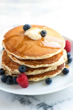 a stack of pancakes with blueberries and raspberries on top