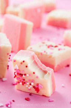 some pink and white pieces of cake with sprinkles on it's surface