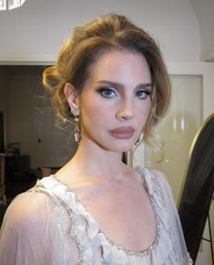 a woman in a white dress is posing for the camera with her hair pulled back