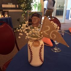 a baseball themed centerpiece with flowers in a vase on top of a blue table cloth