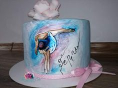 a cake decorated with a ballerina on the side and pink ribbon around the edge