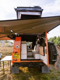 an orange and white camper van parked in the grass with its door open to show it's interior