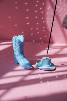 a pair of blue cowboy boots sitting on top of a pink floor next to a lamp