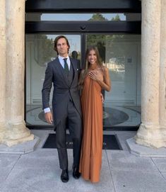 a man and woman standing in front of an entrance to a building with columns on either side