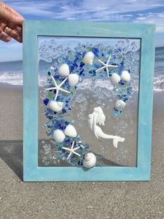 a blue frame with shells and seahorses on the beach