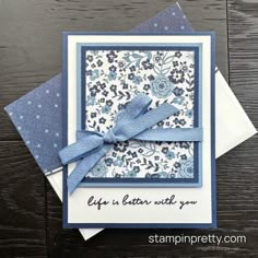 a close up of a card on a wooden table with blue and white flowers in the background