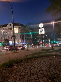 a city street at night with traffic lights and clock tower in the backround