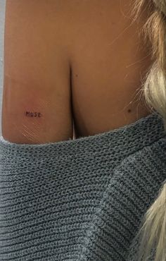 the back of a woman's shoulder with a small tattoo on her left side