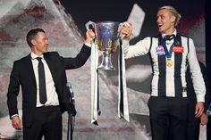 two men in suits hold up a trophy while standing next to each other on stage