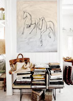 a room filled with lots of books and a large painting on the wall above it