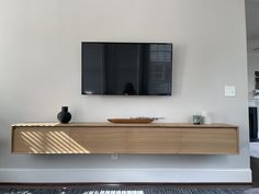 a flat screen tv mounted on the wall above a wooden cabinet in a living room