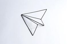 an origami style paper airplane on a white surface with black wire attached to it