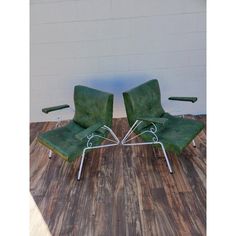 two green chairs sitting on top of a hard wood floor next to a white wall