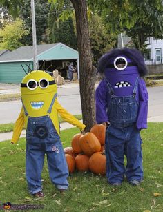 two children dressed up in costumes standing next to each other with pumpkins on the ground