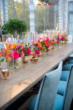 a long table with many vases filled with flowers and candles on top of it