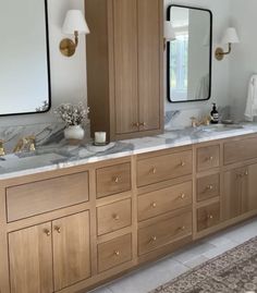 a large bathroom with marble counter tops and wooden cabinets, along with two lamps on either side of the vanity