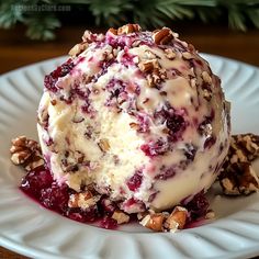 an ice cream sundae with nuts and cranberry sauce on a white plate