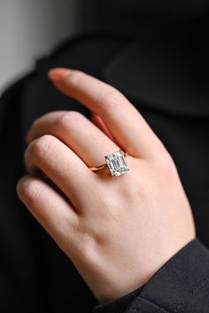 a woman's hand with a diamond ring on her left hand, wearing a black jacket