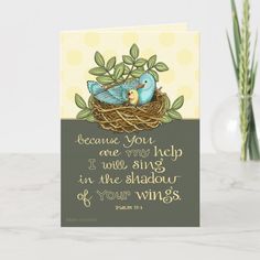 a card with two birds sitting in a nest on top of a table next to a vase