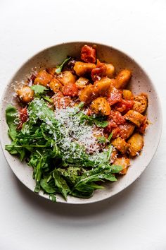 a white bowl filled with pasta and spinach