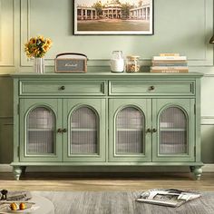 a green cabinet with glass doors and drawers in a living room area next to a painting on the wall