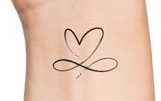 a small heart tattoo on the side of a woman's leg with an arrow in it