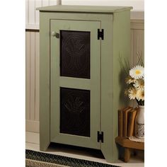 a green cabinet sitting on top of a rug next to a vase with flowers in it