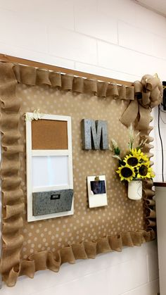 a bulletin board with some pictures on it and flowers in vases next to the letter m