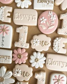 decorated cookies are arranged in the shape of letters and flowers on a brown tablecloth