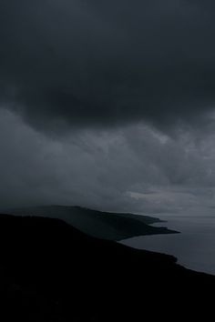 dark clouds hover over the ocean on a cloudy day