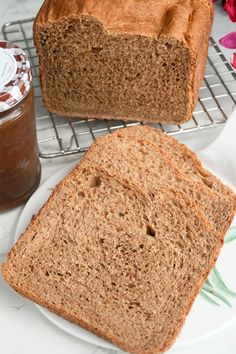 two slices of bread sitting on top of a white plate next to a jar of peanut butter