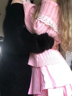 two women in pink dresses hugging each other and one is wearing a black cat on her arm